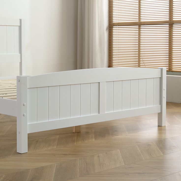 a white bed frame in a room with hardwood floors and windows, along with blinds