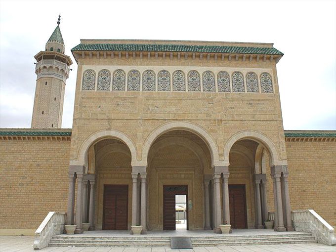 an entrance to a large building with a clock tower in the background