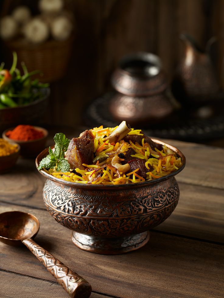 a bowl filled with rice and meat on top of a wooden table