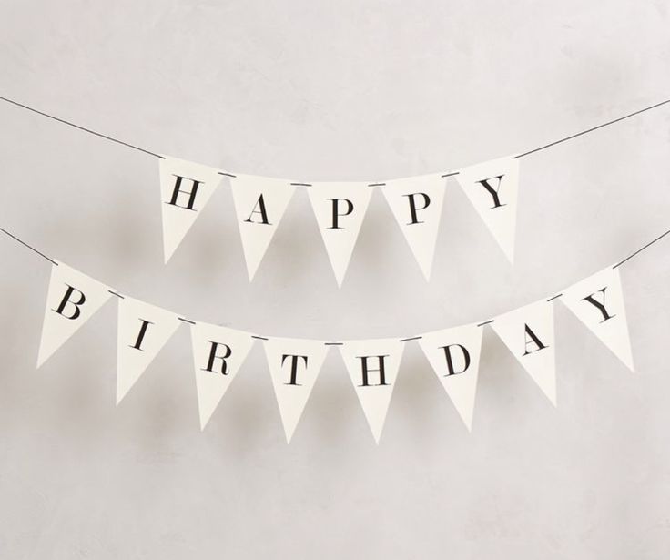 a happy birthday bunting banner hanging from a string on a wall with the words happy birthday in black and white