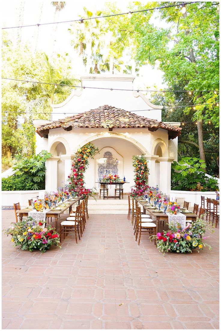 an outdoor dining area with wooden chairs and tables set up for a formal dinner in front of a gazebo