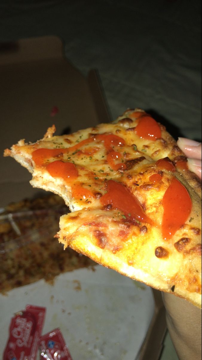 a person holding up a slice of pizza with pepperoni and cheese on it in their hand