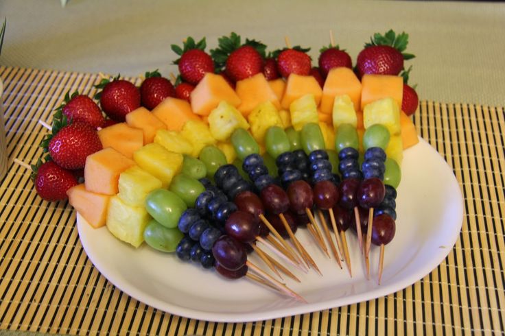 a plate filled with fruits and skewers on top of a table