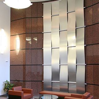 an office lobby with two chairs and a glass table in front of a wall that has metal panels on it