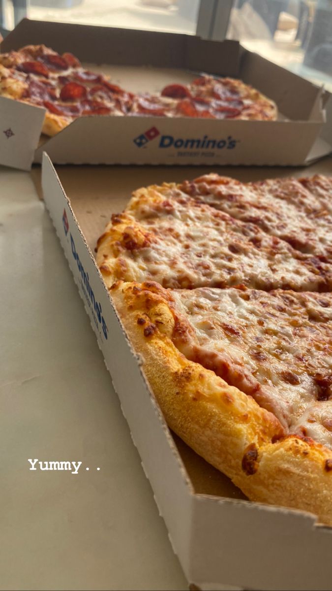 two large pizzas sitting on top of a table next to each other in boxes