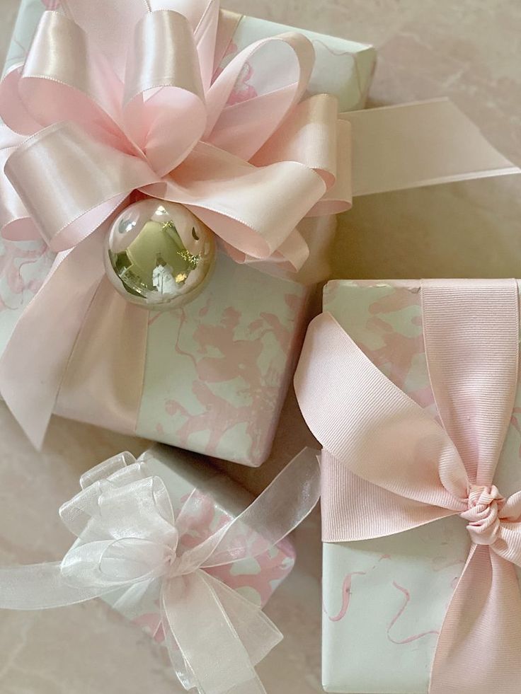 three wrapped presents with pink bows on them