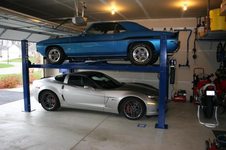 two cars are parked on top of each other in a garage with one car being lifted