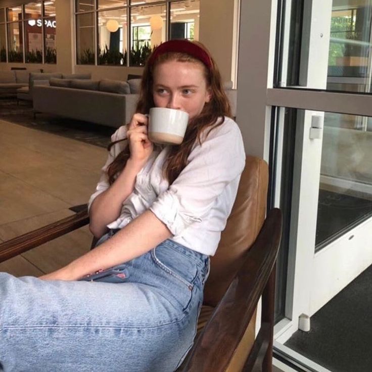 a woman sitting in a chair drinking from a cup