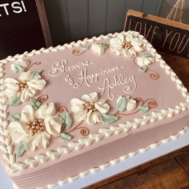 a pink and white birthday cake with flowers on it