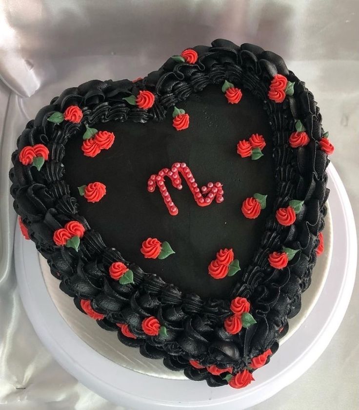 a heart shaped cake with red roses on the top and black frosting in the middle