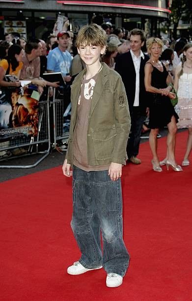 a young boy standing on top of a red carpet next to a group of people