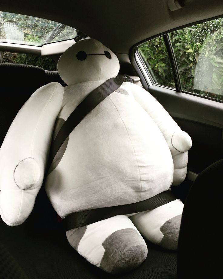 a large white teddy bear sitting in the back seat of a car