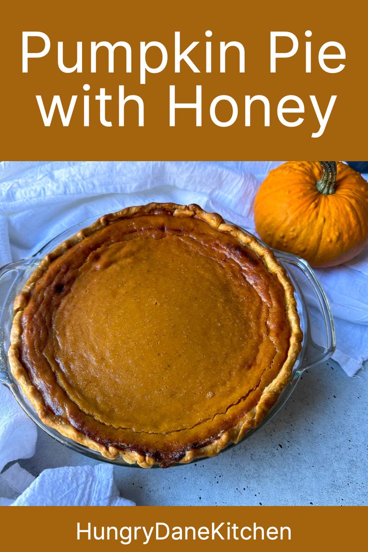 a pumpkin pie with honey crust in a glass pie dish next to an orange pumpkin