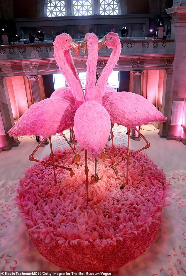 three pink flamingos are standing in the middle of a round area with flowers on it