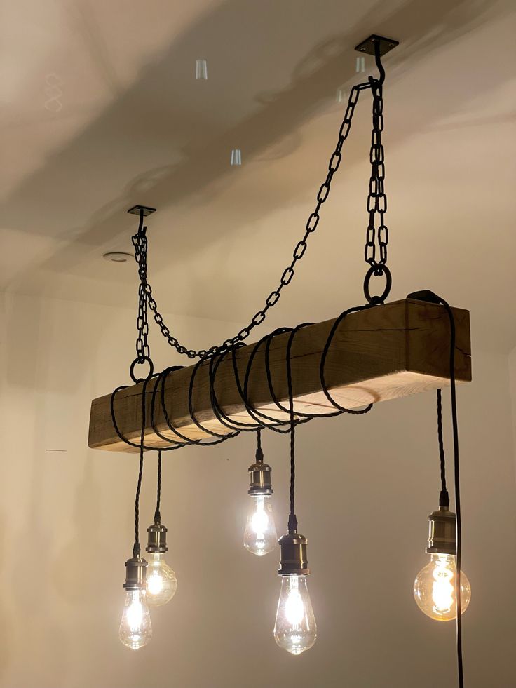 several light bulbs are hanging from a wooden beam with chains and lights on the ceiling