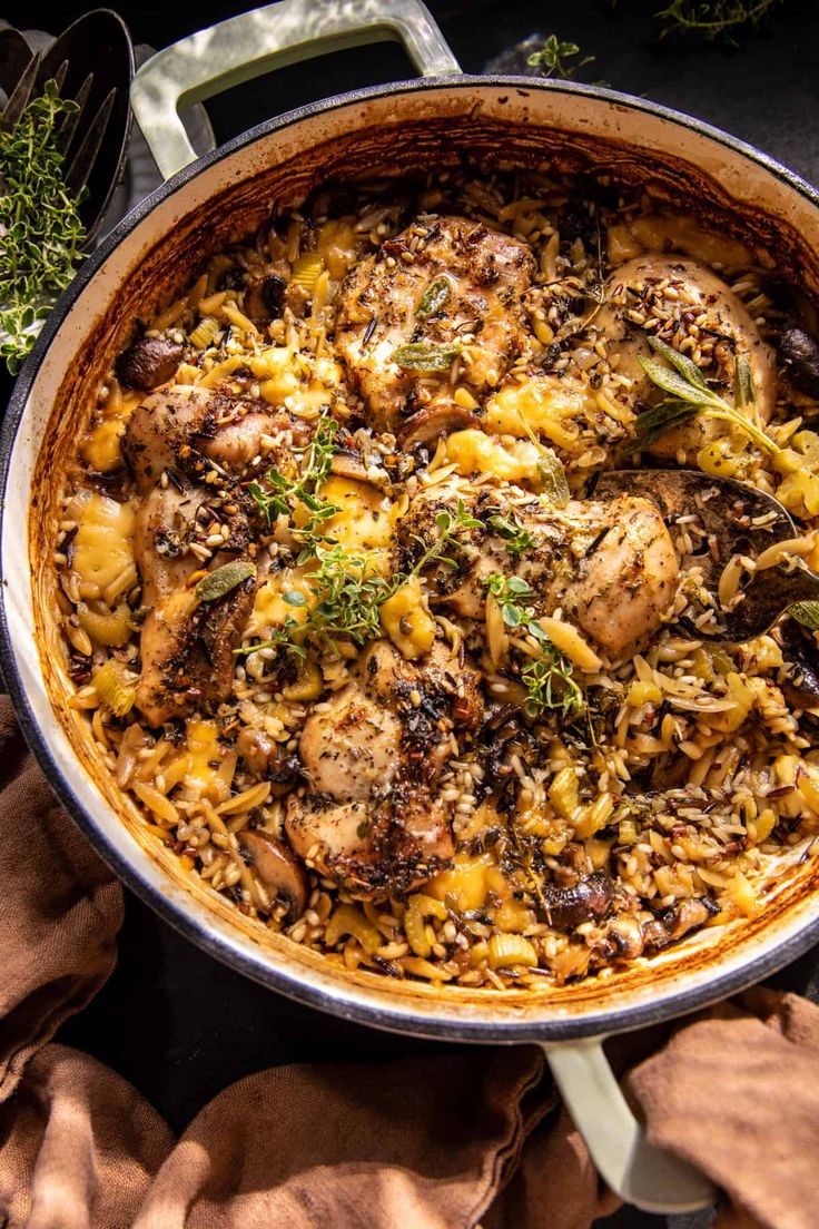 a pot filled with chicken and rice on top of a table next to some utensils