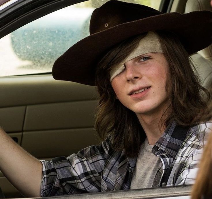 a woman wearing a cowboy hat sitting in the driver's seat of a car