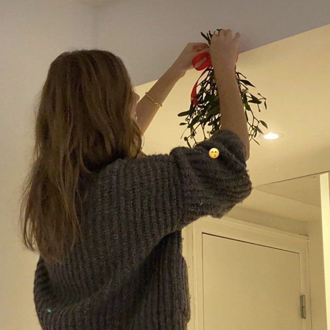 a woman is hanging flowers from the ceiling