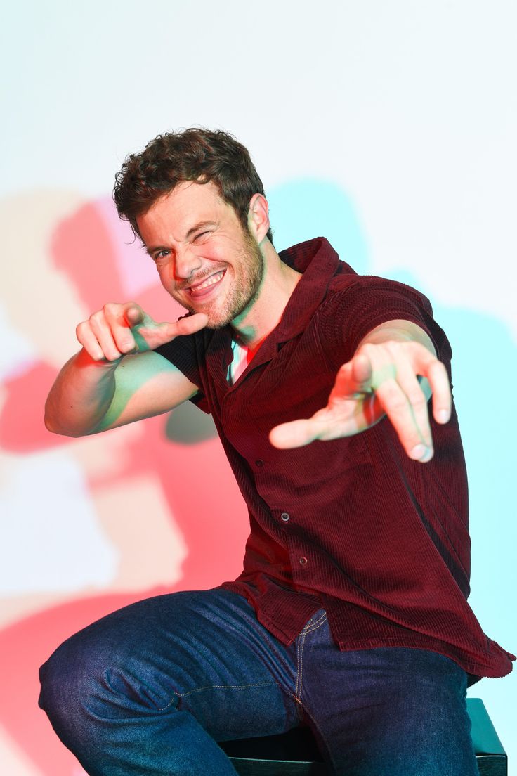 a man sitting on top of a stool making a funny face with his hands and fingers