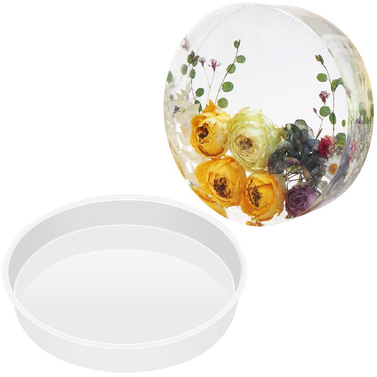 an empty bowl with flowers in it next to a plastic container that has the lid open