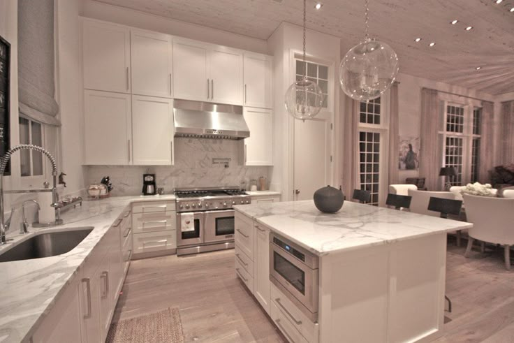 a large kitchen with marble counter tops and white cabinets