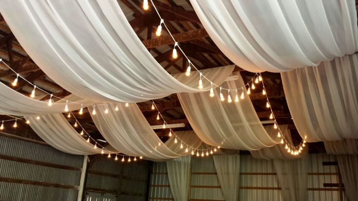 the ceiling is covered with white drapes and string lights