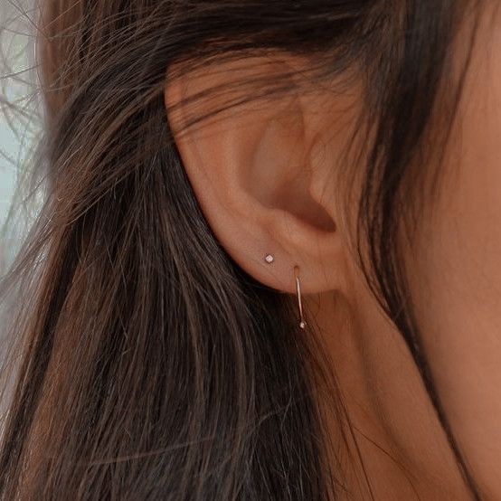 a close up of a woman's ear wearing a pair of tiny diamond earrings