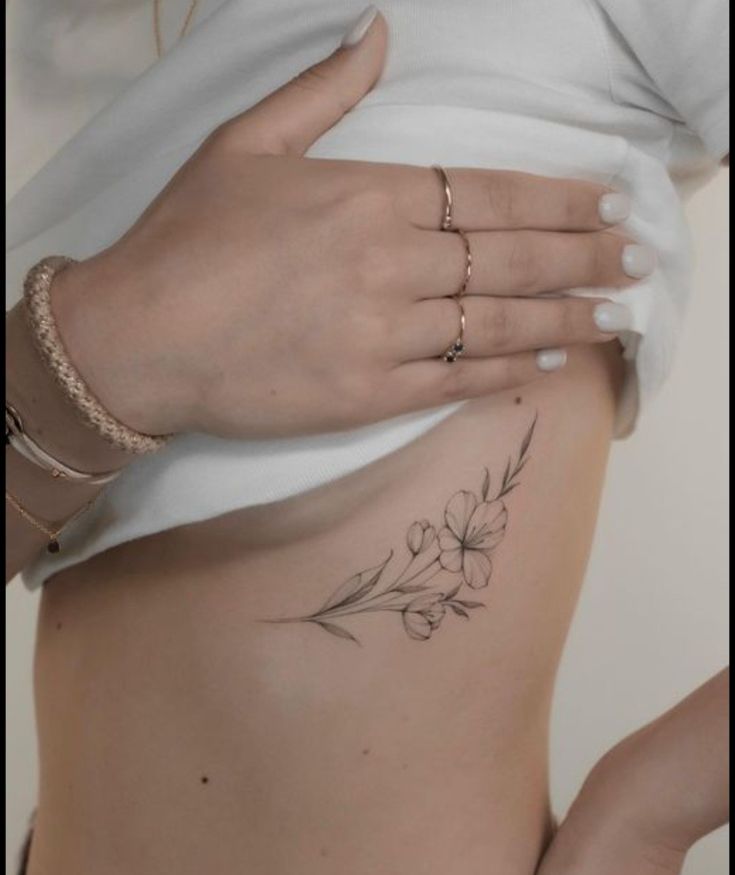 a woman's stomach with flowers on it and her hand resting on the side