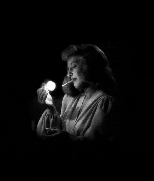 a woman holding a lit candle in her right hand and looking at the light on her left