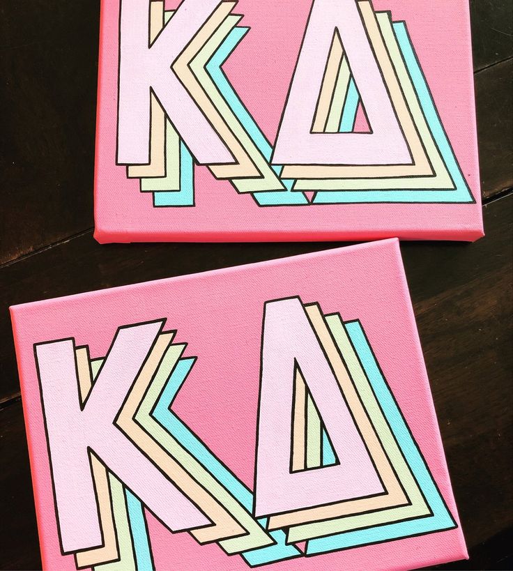 two pink canvases with the letters k and d painted on them are sitting on a table