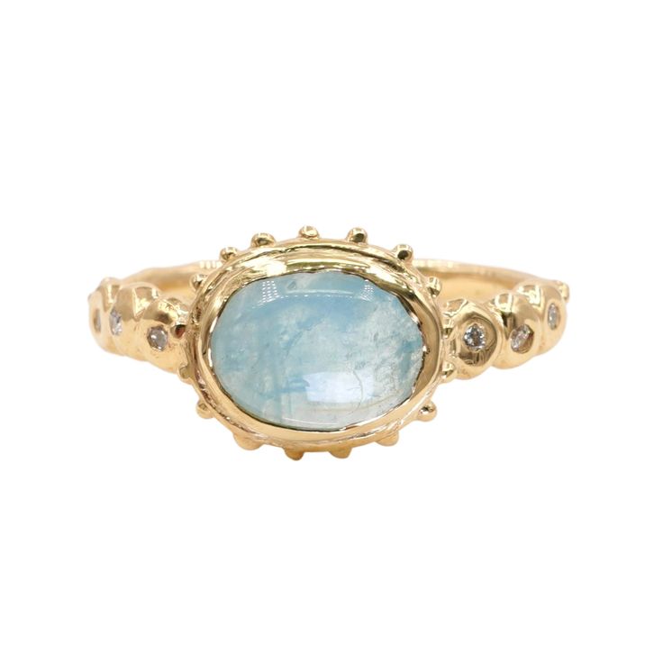 a gold ring with a blue stone in the center and diamonds around it, on a white background