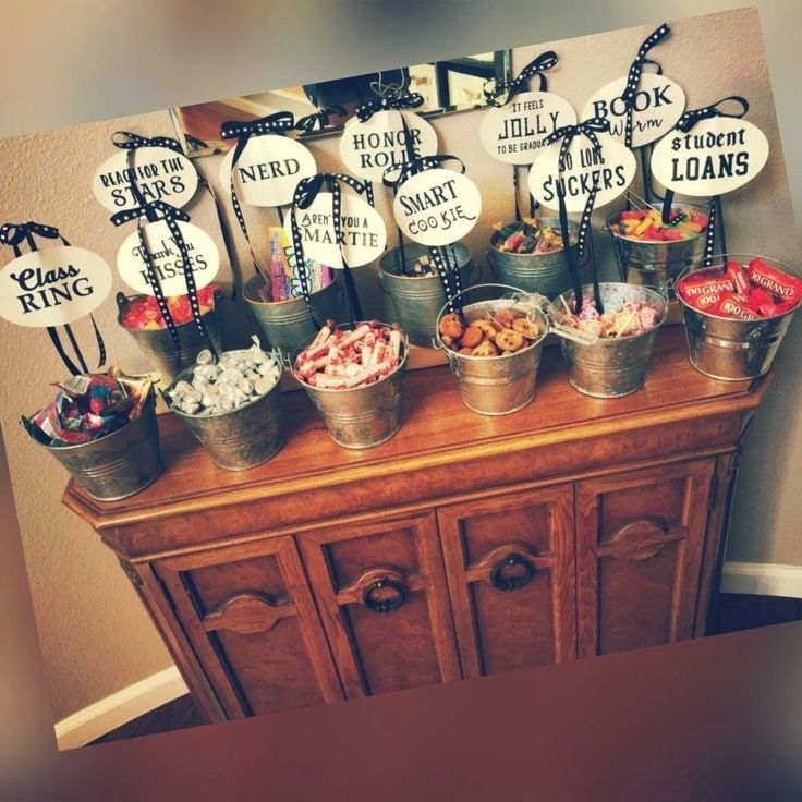 a table topped with buckets filled with lots of candy next to a sign that says,