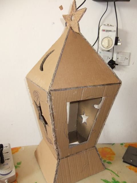 a cardboard house with a star on the top and an open window in the middle