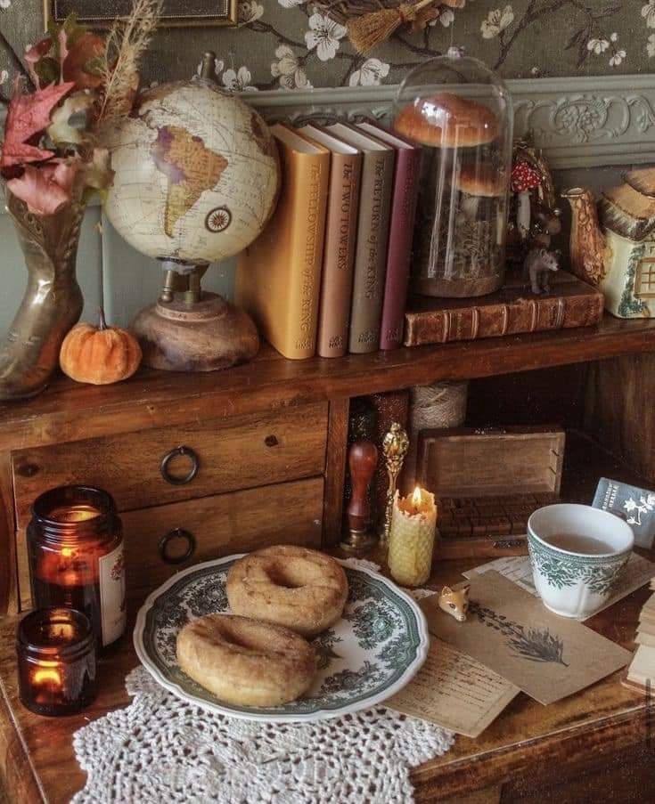 a table topped with books and donuts on top of a wooden desk next to a candle