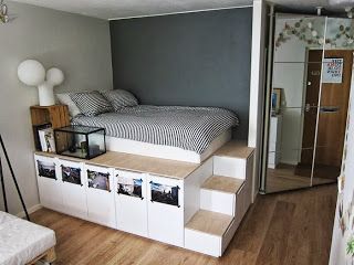 a bed sitting on top of a wooden floor next to a white shelf filled with pictures