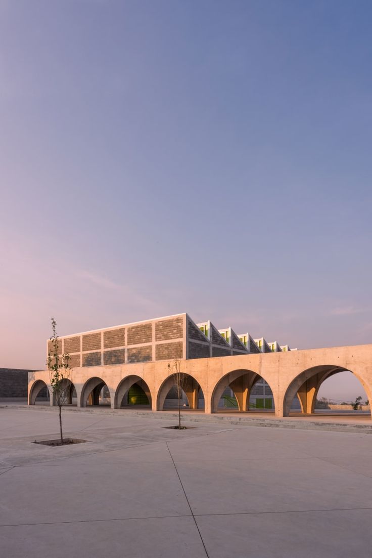 the building is made of concrete and has arches on both sides that lead into an open area