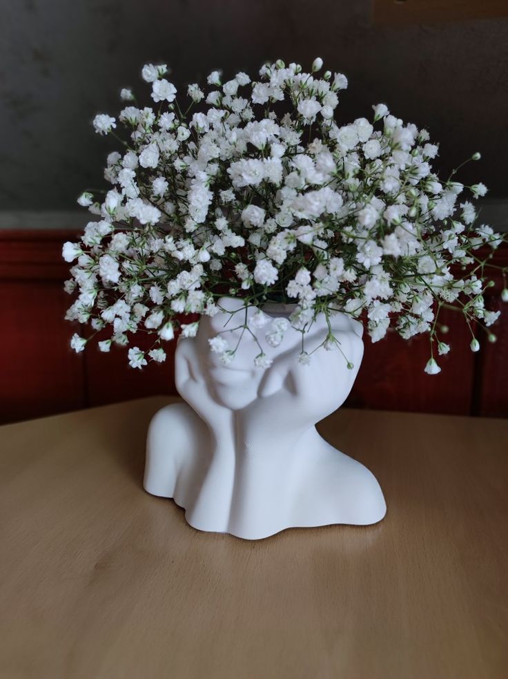 a vase filled with white flowers on top of a wooden table