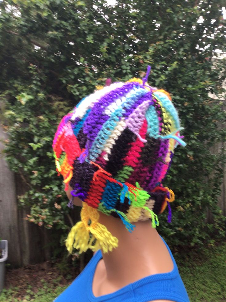 a person wearing a multicolored knitted hat on top of their head in front of a tree