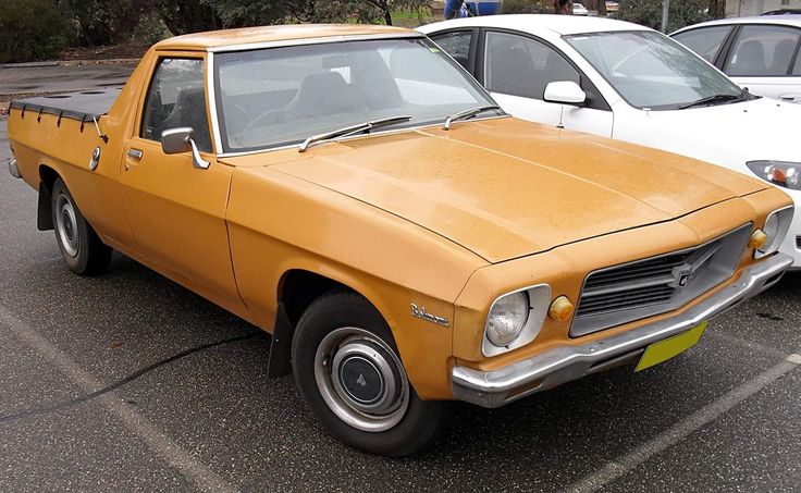 an orange car parked in a parking lot next to other cars