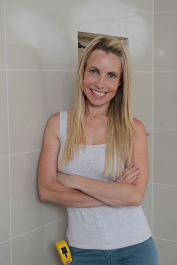 a woman standing in front of a shower with her arms crossed and smiling at the camera