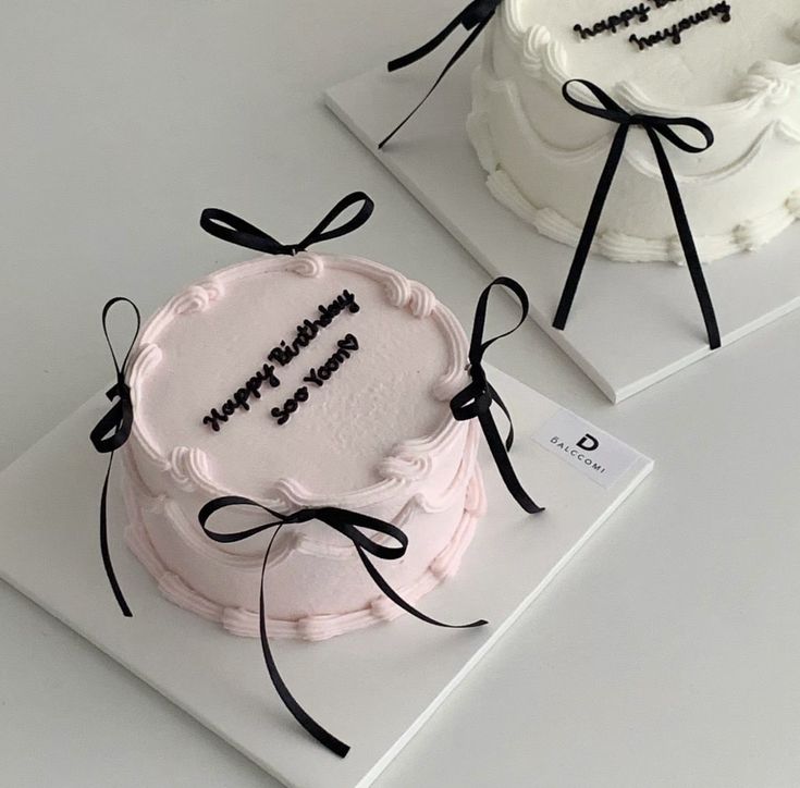 two white cakes with black writing on them sitting on top of each other in front of a price tag