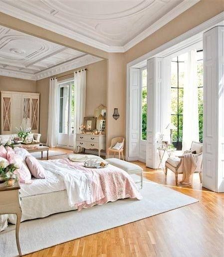 an elegant bedroom with white furniture and wood flooring, along with french doors leading to the outside