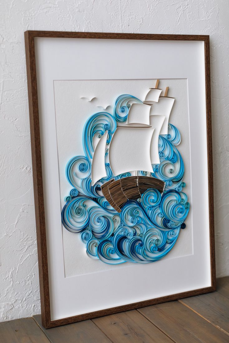 a paper cut out of a ship in the ocean with blue waves and swirls