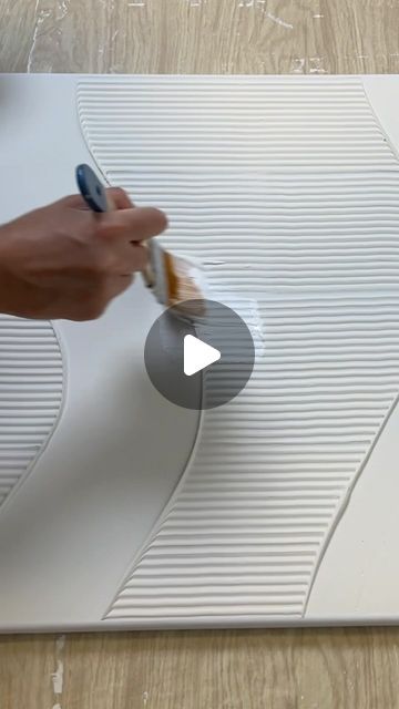 a person is using a brush to paint the surface of a white board with wavy lines on it