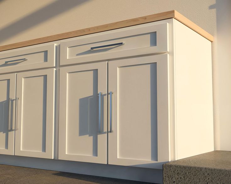 a white kitchen cabinet with two doors and three cupboards on each side, in front of a wall