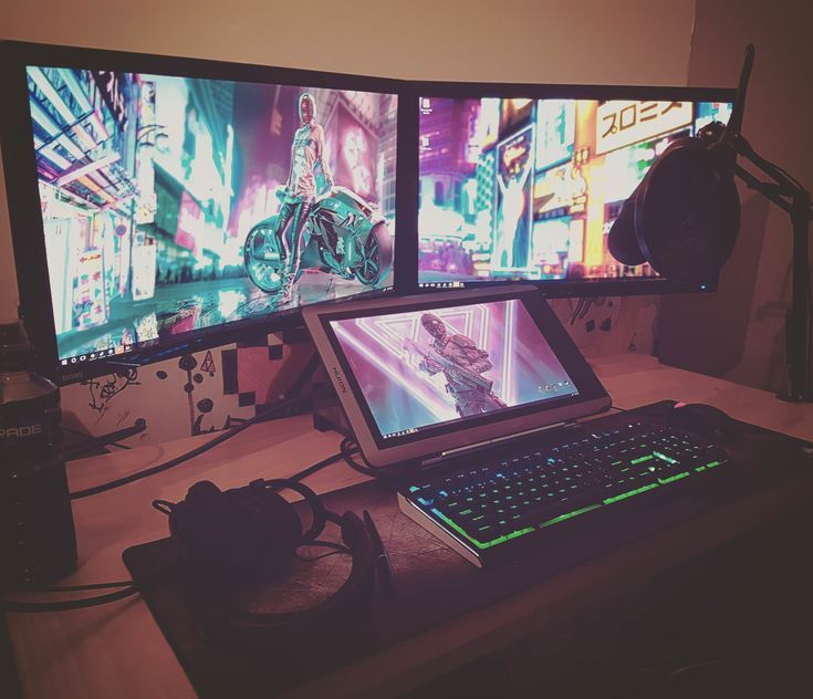 a laptop computer sitting on top of a desk next to two monitors with video games on them