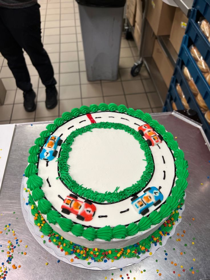 a birthday cake with cars on it sitting on a table in a room filled with other items