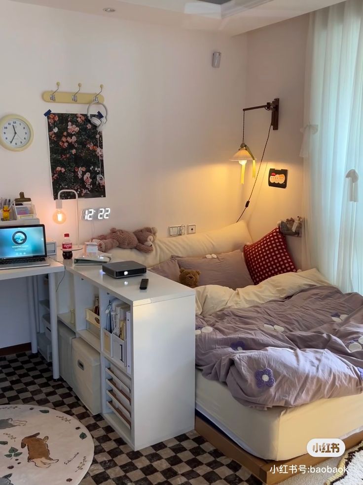 a room with a bed, desk and computer on top of the table in it