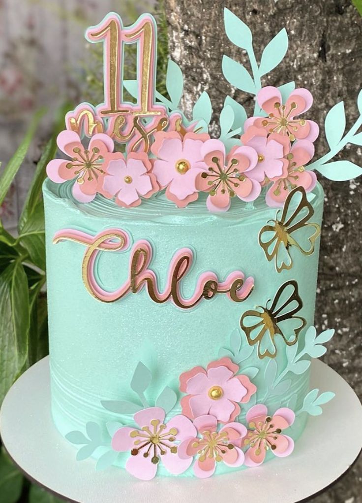 a blue cake with pink flowers and butterflies on it