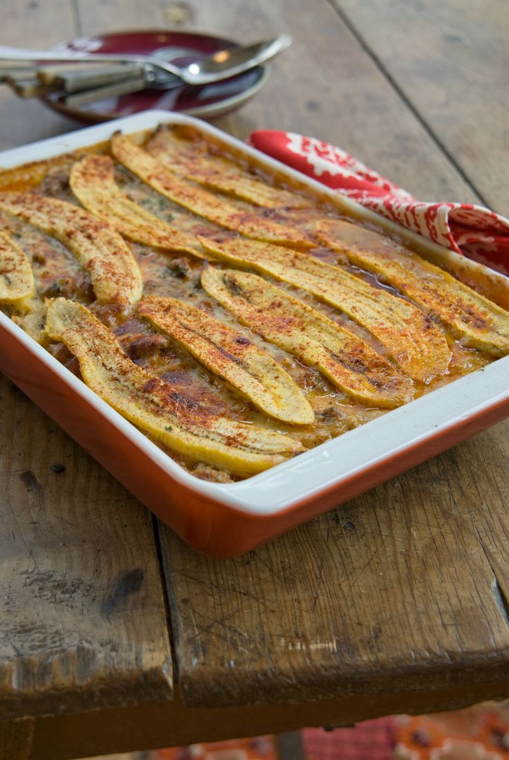 a casserole dish on a wooden table with utensils